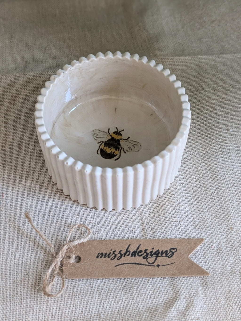 A small neutral beige ceramic trinket ring bowl with a fluted rim and a printed bumblebee design inside perfect gift