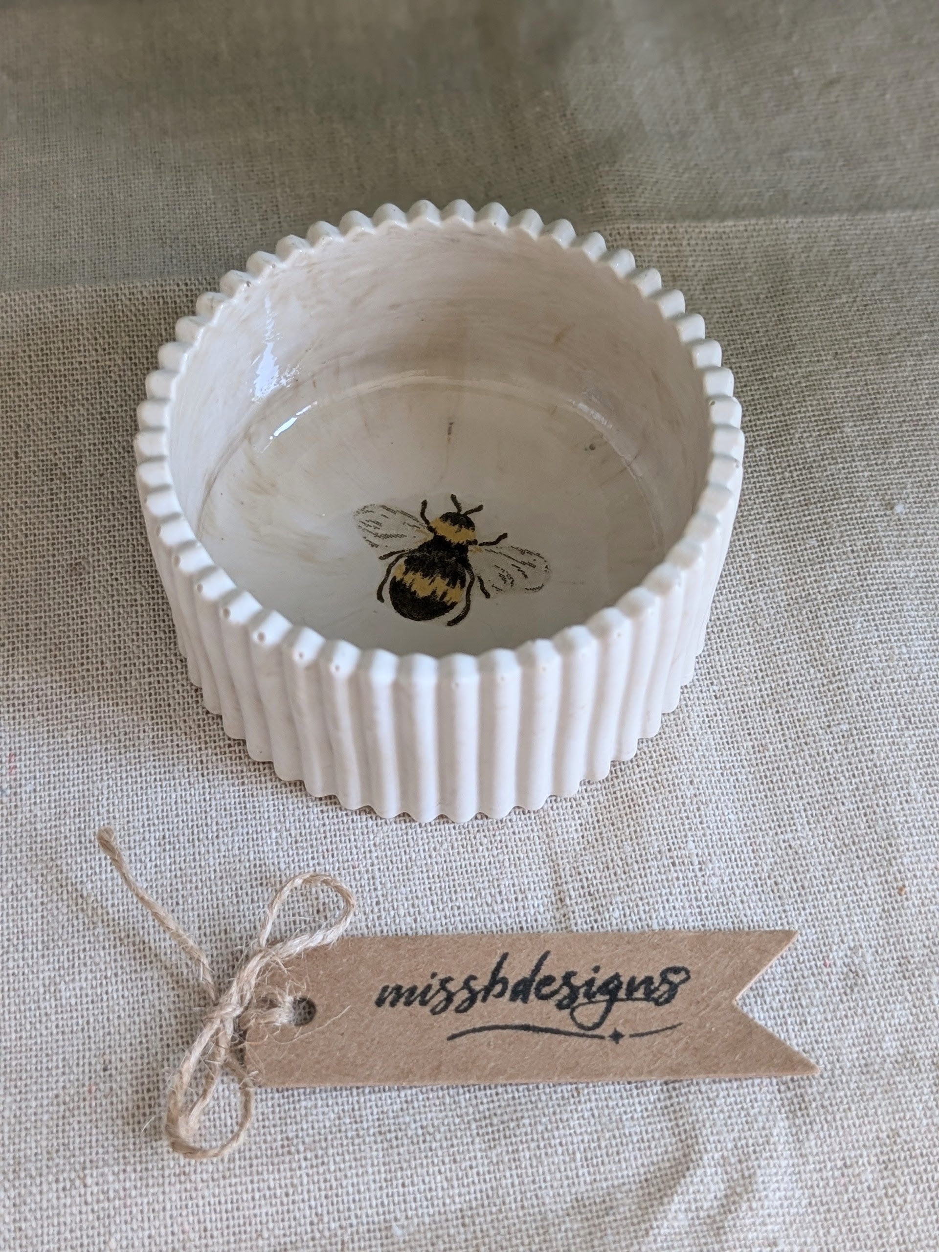 A small neutral beige ceramic trinket ring bowl with a fluted rim and a printed bumblebee design inside perfect gift